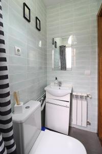 a white bathroom with a toilet and a sink at Apartamentos El Cuco in Boó de Piélagos