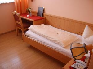 a small room with a bed and a table with a laptop at Hotel-Gasthof Zur Rose in Weißenhorn