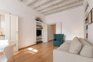 a white living room with a couch and a blue chair at Naviglio, sweet dreams in the heart of the fun in Milan