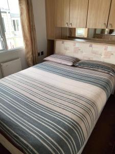 a large bed with a blue and white striped blanket at ChapmanHolidayLets Cayton Bay in Cayton