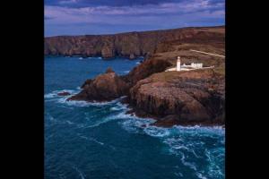 a lighthouse on the side of a rocky island in the ocean at Atlantic View Apartment in Dungloe