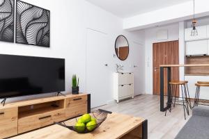 a living room with a television and a table at Apartament Maxim Premium in Darłowo