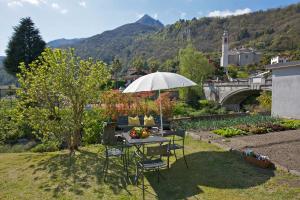 un tavolo e sedie con ombrellone in un cortile di Casa Limoni a Cannero Riviera