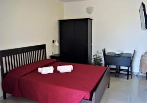 a bedroom with a red bed with two towels on it at Oasi Di Casablanca in Lampedusa