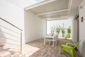 a dining room with a white table and green chairs at Casa vacanza Torre Specchia in Torre Specchia Ruggeri