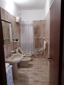een badkamer met 2 toiletten, een wastafel en een douche bij Small Flat in Scafa