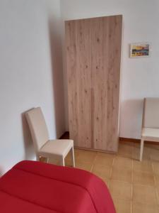 een kamer met een bed en twee stoelen en een deur bij Small Flat in Scafa