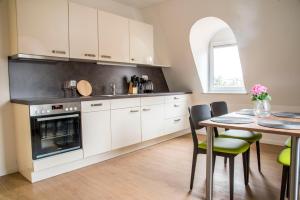 Una cocina con gabinetes blancos y una mesa con sillas. en Villa Müller, en Bad Kissingen