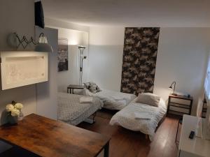 Kleines Zimmer mit 2 Betten und einem Tisch in der Unterkunft Wool INN Studio in the Forest in Noisy-sur-École