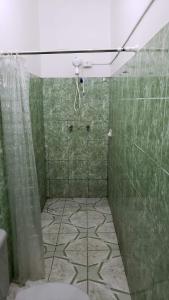 y baño con ducha, aseo y azulejos verdes. en Suítes em Parintins, en Parintins