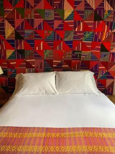 białe łóżko w sypialni z kolorową ścianą w obiekcie Casa Chula / Céntrica con jardín, terraza y parqueo w mieście Antigua Guatemala