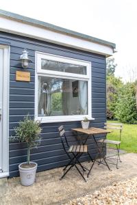 uma pequena casa azul com uma mesa e uma janela em The Nook em West Mersea
