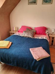 sypialnia z dużym niebieskim łóżkiem z różowymi poduszkami w obiekcie Ellias w mieście Pont-lʼAbbé