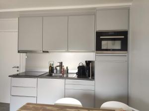 a white kitchen with a sink and a microwave at SeaLodge4you in Bredene