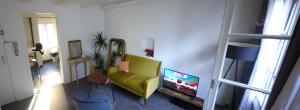 a living room with a green couch and a tv at Appartement cosy rue Sainte Madeleine in Strasbourg