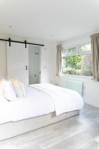 a white bedroom with a large bed and a window at The Nook in West Mersea
