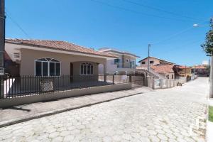 une maison avec une clôture sur le côté d'une rue dans l'établissement Casa com 03 dormitórios, à Bombinhas