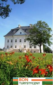 a large white house with a tree and flowers at Hotel Pałac Borynia in Jastrzębie Zdrój