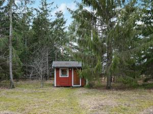 een kleine rode hut in een veld met bomen bij 4 person holiday home in L RBRO in Lärbro