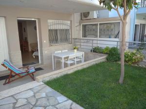 eine Terrasse mit einem weißen Tisch und einem Baum in der Unterkunft ΔΕΣΠΟΙΝΑ in Néa Péramos