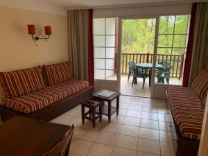 a living room with two couches and a table and a balcony at Appartement dans résidence de vacances in Biscarrosse