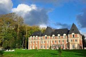 un grand bâtiment avec un toit noir sur un champ vert dans l'établissement Résidence Goélia Les Portes d'Étretat, à Maniquerville