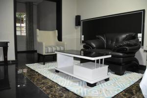a living room with a black leather couch and a coffee table at Annavilla7 Lilongwe Aparthotel in Lilongwe