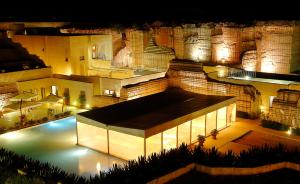 a view of a building with a swimming pool at night at Cave Bianche Hotel in Favignana