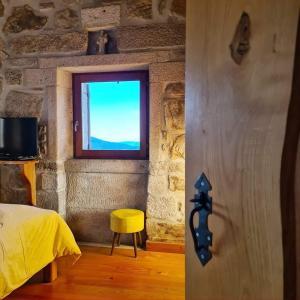 a bedroom with a window and a yellow stool at Cardenha da Bessada in Branda de Santo António