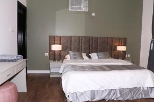 a bedroom with a large bed with two lamps at مندرين للشقق المخدومة in Taif