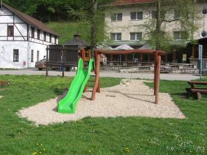 a playground with a green slide in the grass at Hotel Skalní Mlýn in Blansko