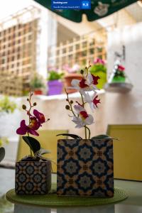 dos jarrones con flores en ellos sentados en una mesa en The Zen Apartment Athens, en Atenas