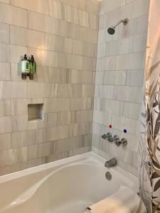 a bathroom with a white bath tub with a shower at Casa Chula / Céntrica con jardín, terraza y parqueo in Antigua Guatemala