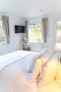 een witte slaapkamer met een bed en een raam bij The Nook in West Mersea