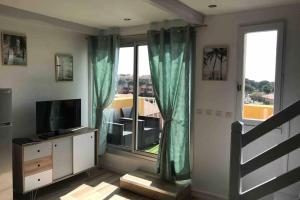 een woonkamer met een televisie en een groot raam bij Résidence Port Soleil Duplex T3 46 m2 climatisé in Gruissan