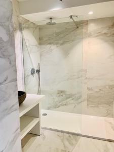 a bathroom with a shower with white marble walls at Even Aan Zee - Largo in Nieuwpoort