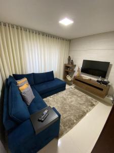 een woonkamer met een blauwe bank en een tv bij Casa Temporada da Jojo in Capitólio