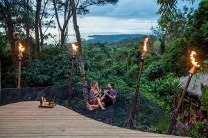 Ein Mann und eine Frau sitzen auf einem Gehweg im Wald in der Unterkunft Selva Armonia Immersive Jungle Resort in Uvita