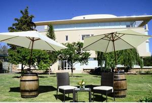 two umbrellas and chairs and a table and two barrels at Hotel Finca Hermitage in Mendoza