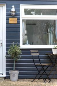 a sign on a blue house with a chair and a window at The Nook in West Mersea +16 photos