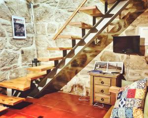 a room with a stone wall with wooden stairs at Cardenha da Bessada in Branda de Santo António