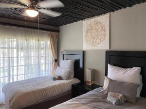 um quarto com 2 camas e uma ventoinha de tecto em Sasavona Game Lodge em Bela-Bela