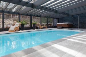 a swimming pool in a house with a glass ceiling at B&B La Villa d'Olne in Spa