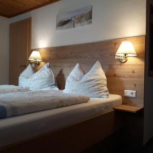 ein Schlafzimmer mit einem Bett mit weißen Kissen und zwei Lichtern in der Unterkunft Ferienhaus Hintersee in Hintersee