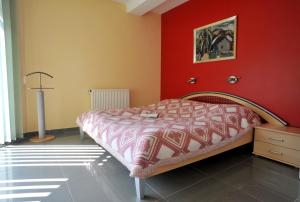 ザラカロシュにあるMarianna Apartmanházの赤い壁のベッドルーム1室(ベッド1台付)