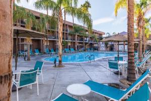 un complexe avec une piscine, des chaises et des palmiers dans l'établissement WorldMark Palm Springs, à Palm Springs