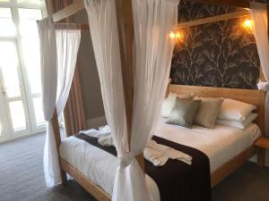 um quarto com uma cama de dossel e cortinas brancas em The Havelock em Shanklin