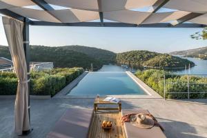 a house with a swimming pool and a view of a river at Domotel Agios Nikolaos Suites Resort in Sivota
