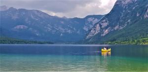 a couple of people sitting in a yellow boat on a lake at 7 LAKES apartment in Bohinj