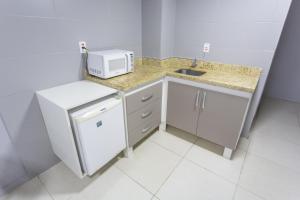 uma pequena cozinha com um lavatório e um micro-ondas em USEHOTEL - A uma quadra do complexo hospitalar Santa Casa em Porto Alegre